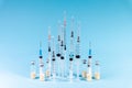 Medical syringes and glass vials of medicine are lined up on a blue background. The concept of mass vaccination against