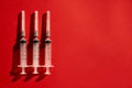 Medical syringes needles on red background with highlights and shadows. Copy space for text Royalty Free Stock Photo