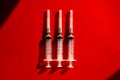 Medical syringes needles on red background with highlights and shadows