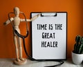 Medical table with a wooden person along with a stethoscope. Inscription TIME IS THE GREAT HEALER on the clipboard with the holder