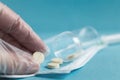 Medical tablets close on the blue background.paramedic hand holds pill. Coronavirus, flu respiratory disease concept