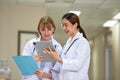 Medical team discussing about case over digital tablet in corridor at hospital Royalty Free Stock Photo