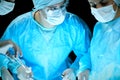 Medical team performing operation. Group of surgeon at work in operating theatre toned in blue Royalty Free Stock Photo