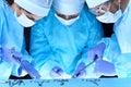 Medical team performing operation. Group of surgeons at work in operating theater toned in blue Royalty Free Stock Photo