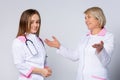 Medical team of two professional doctors talking in meeting. Senior female chief physician helping young female doctor, discussing Royalty Free Stock Photo