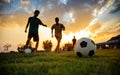 Silhouette action sport outdoors of a group of kids having fun playing soccer football for exercise in community rural area under Royalty Free Stock Photo