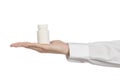 Medical theme: doctor's hand holding a white empty jar of pills on a white background