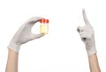 Medical theme: doctor's hand in white gloves holding a transparent container with the analysis of urine on a white background