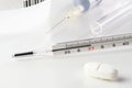 Medical thermometer, pill, vaccine in medical syringe and glass tube on white