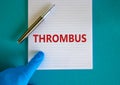 Medical and thrombus symbol. Doctor hand, metalic pen. White note with the word `thrombus`. Beautiful blue background. Doctor ha