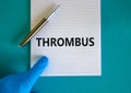 Medical and thrombus symbol. Doctor hand, metalic pen. White note with the word `thrombus`. Beautiful blue background. Doctor ha