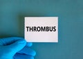 Medical and thrombus symbol. Doctor hand. White card with the word `thrombus`. Beautiful blue background. Doctor hand in blue