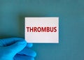 Medical and thrombus symbol. Doctor hand. White card with the word `thrombus`. Beautiful blue background. Doctor hand in blue