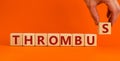 Medical and and thrombus symbol. Wooden cubes with the word `thrombus`. Beautiful orange background. Doctor hand. Medical and