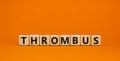 Medical and and thrombus symbol. Wooden cubes with the word `thrombus`. Beautiful orange background. Medical and thrombus concep