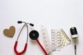 Medical tools on white background with copyspace for text. Wooden heart, red stethoscope. pills container, blisters, pulse