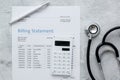 Medical treatmant billing statement with stethoscope and calculator on stone background top view Royalty Free Stock Photo