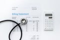 Medical treatmant billing statement with stethoscope and calculator on white background top view