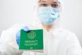 Medical UK healthcare security officer worker in personal protective equipment holding green immunity passport ID card