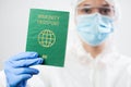 Medical US healthcare security officer worker in personal protective equipment holding green immunity passport ID card