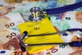 Medical vaccination cost concept - Stethoscope and yellow international certificate of vaccination on Euro paper money bank notes