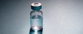 Medical vial for injection on gray blue background, transparent glass bottle, drug medicine vaccine dose