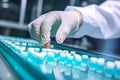 Medical vials production line: hand with sanitary gloves checking pharmaceutical bottles in a sterile factory