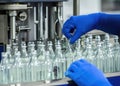 Medical Vials Production Line: Hand with Sanitary Gloves Checking Pharmaceutical Glass Bottles in a Sterile Factory Royalty Free Stock Photo