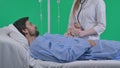 Adult man patient laying in bed with drip, female nurse next to men checking his pulse holding wrist. Isolated on chroma Royalty Free Stock Photo