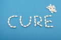 Medical white pills, tablets forming the word cure on blue background Royalty Free Stock Photo