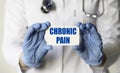 A medical worker in gloves holds a card with the text CHRONIC PAIN. Medical concept Royalty Free Stock Photo