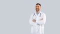 Medical worker. Happy male doctor in uniform posing with folded arms over grey studio background, panorama, free space Royalty Free Stock Photo