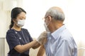 Medical worker or nurse perform a vaccine injection to senior Asian man in clinic