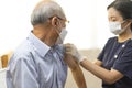 Medical worker or nurse perform a vaccine injection to senior Asian man in clinic