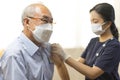 Medical worker or nurse perform a vaccine injection to senior Asian man in clinic