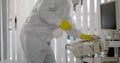 Medical worker in ppe doing sanitization of equipment in hospital room