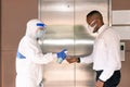 A medical worker in PPE suits use alcohol gel washing hand the employee in front of elevator