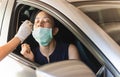 Medical worker taking nasal swab from woman in car to test for covid-19 infection. Royalty Free Stock Photo