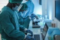 Medical workers in hazmat suit working with laptop computer and micoroscope inside laboratory hospital during coronavirus outbreak