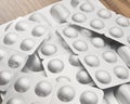 Medicaments on a wooden table. Many tablets in silvery blisters