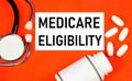 Medicare eligibility. Text label in the folder on the background of medicines. Royalty Free Stock Photo