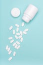 Medication bottle and white pills spilled on blue pastel colored background. Medication and prescription pills flat lay background Royalty Free Stock Photo