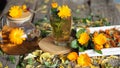 Medicinal autumn background. Herbal healthy marigold tea with a teapot, dried and fresh flowers on an autumn wooden background