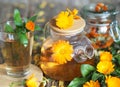 Medicinal autumn background. Herbal healthy marigold tea with a teapot, dried and fresh flowers on an autumn wooden background