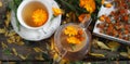 Medicinal autumn background. Herbal healthy marigold tea with a teapot, dried and fresh flowers on a wooden background with autumn