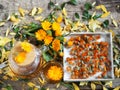 Medicinal autumn background. Herbal healthy marigold tea with a teapot, dried and fresh flowers on a wooden background with autumn
