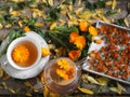 Medicinal autumn background. Herbal healthy marigold tea with a teapot, dried and fresh flowers on a wooden background with autumn