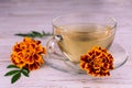 Medicinal marigold tea in a transparent cup on a white wooden background. Royalty Free Stock Photo