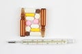 Medicinal tablets, thermometer and ampoule on a white background