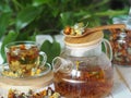 Medicinal tea made from dried flowers of calendula and marigolds on a wooden table and with green leaves in the background. The Royalty Free Stock Photo